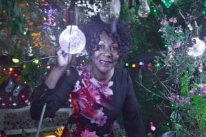 A photo of Andrea Connor from her article in Peterborough Telegraph, showing her sitting beneath stunning fairy lights in her Night Garden.