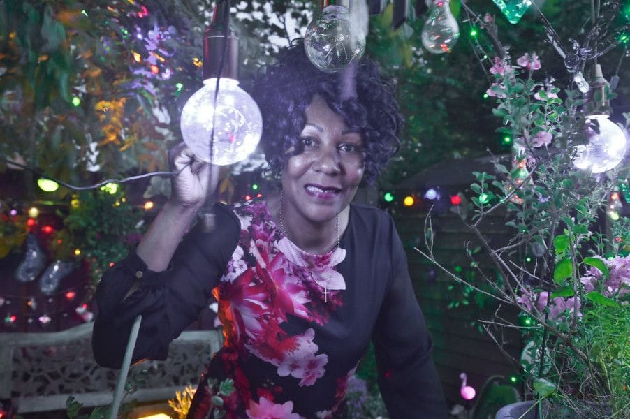 A photo of Andrea Connor from her article in Peterborough Telegraph, showing her sitting beneath stunning fairy lights in her Night Garden.