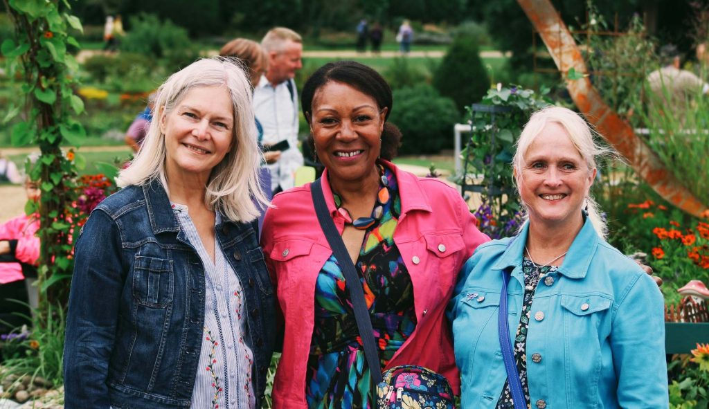 A photo of Andrea, and the friends that helped her prepare for Gardener's World, posing in front of her Wonderland Border garden deisgn. Located at Audley End House at BBC Gardener's World Autumn Fair 2026.