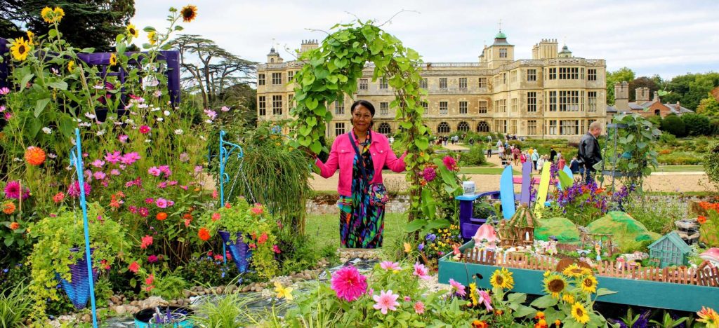 A photo of Andrea posing in the willow archway of her Wonderland Garden in front of Audley End House at the BBC Gardener's World 2026 Autumn Fair.